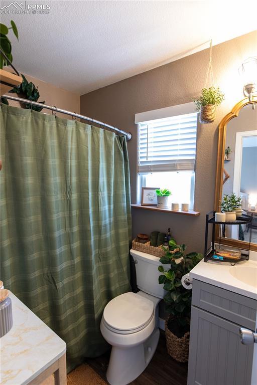 bathroom with vanity, curtained shower, toilet, and a textured ceiling