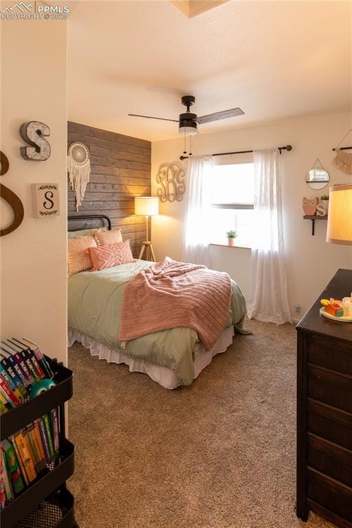 carpeted bedroom featuring ceiling fan and wooden walls