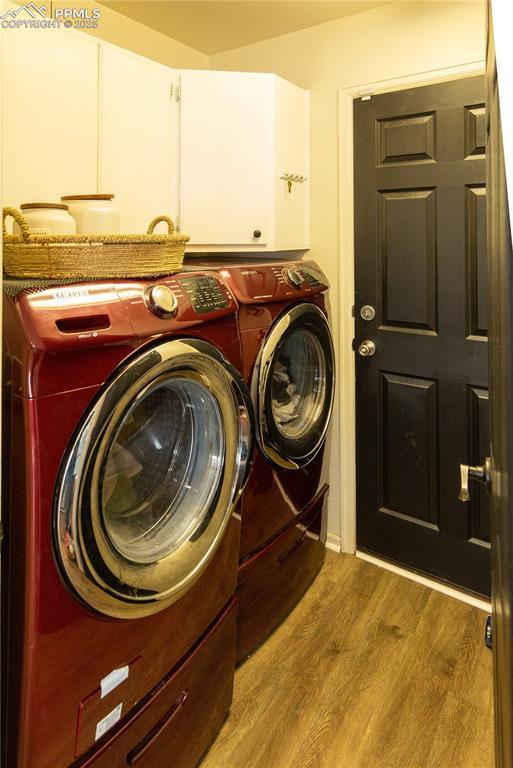 laundry room featuring cabinets, separate washer and dryer, and hardwood / wood-style floors