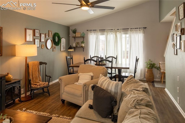 living room with ceiling fan, dark hardwood / wood-style floors, vaulted ceiling, and a wood stove