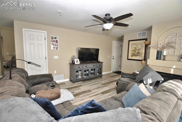 living room featuring a textured ceiling, ceiling fan, and light wood-type flooring