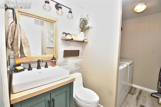 bathroom with vanity, hardwood / wood-style flooring, washer and dryer, and toilet