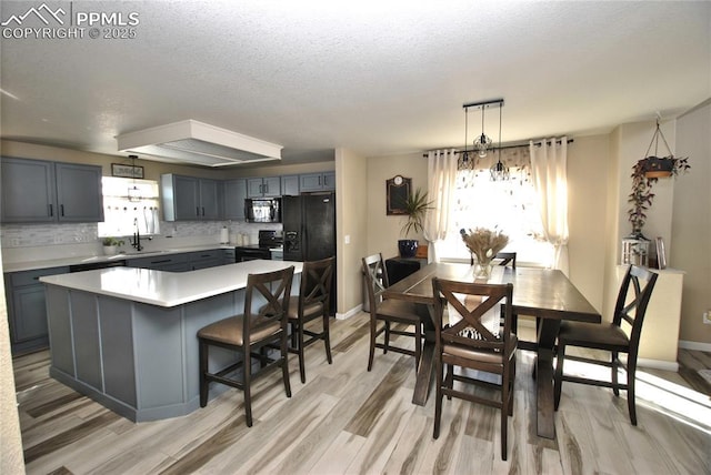 kitchen with tasteful backsplash, a kitchen island, a wealth of natural light, and black appliances