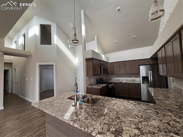 kitchen with decorative light fixtures, sink, dark brown cabinetry, kitchen peninsula, and stainless steel appliances