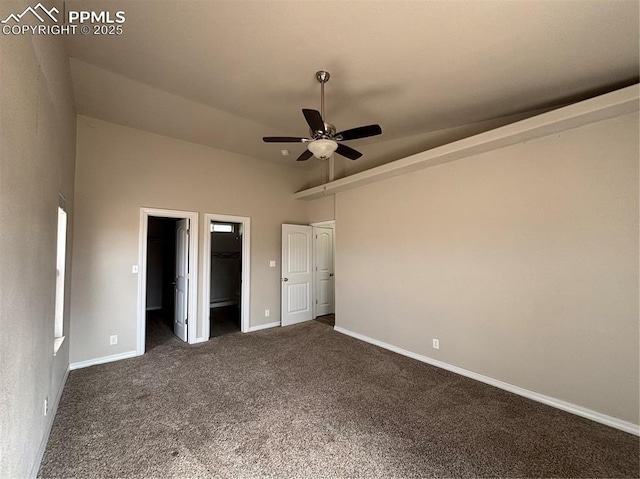 unfurnished bedroom with ceiling fan, a spacious closet, and dark colored carpet