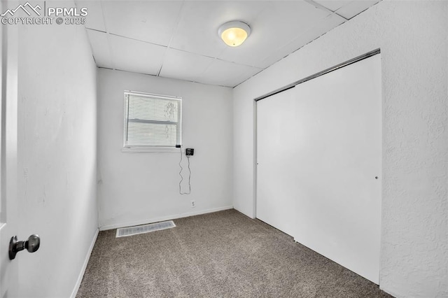 carpeted spare room featuring a paneled ceiling