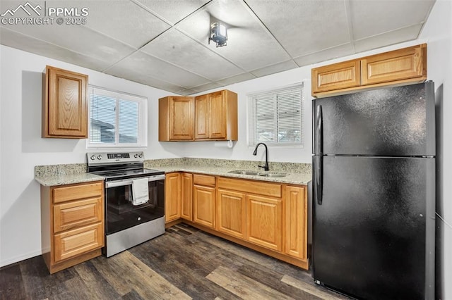 kitchen with stainless steel electric stove, sink, light stone counters, black fridge, and dark wood-type flooring