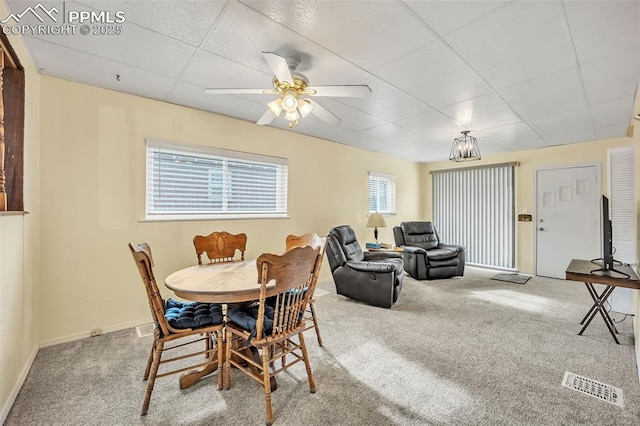 carpeted dining area featuring a drop ceiling and ceiling fan