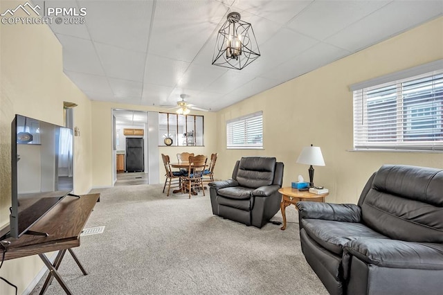 living room featuring ceiling fan with notable chandelier and carpet