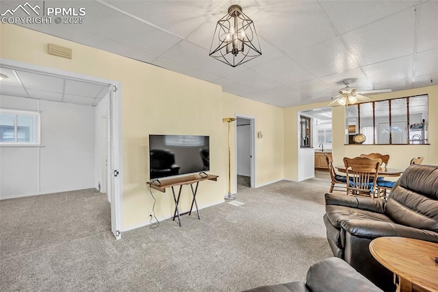 carpeted living room with a paneled ceiling and ceiling fan with notable chandelier