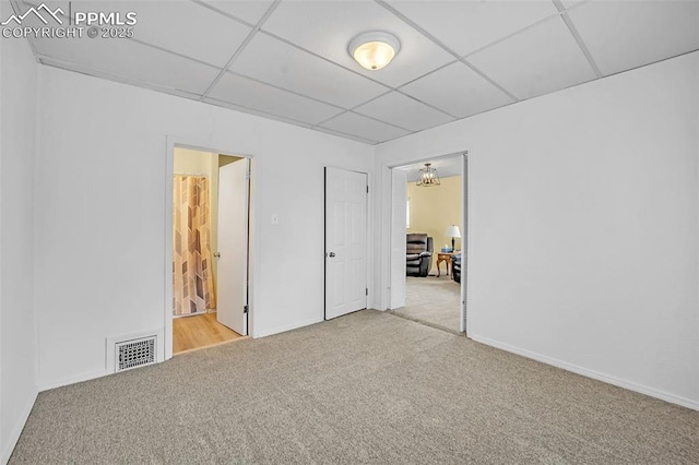 unfurnished bedroom featuring light carpet, a paneled ceiling, and ensuite bathroom