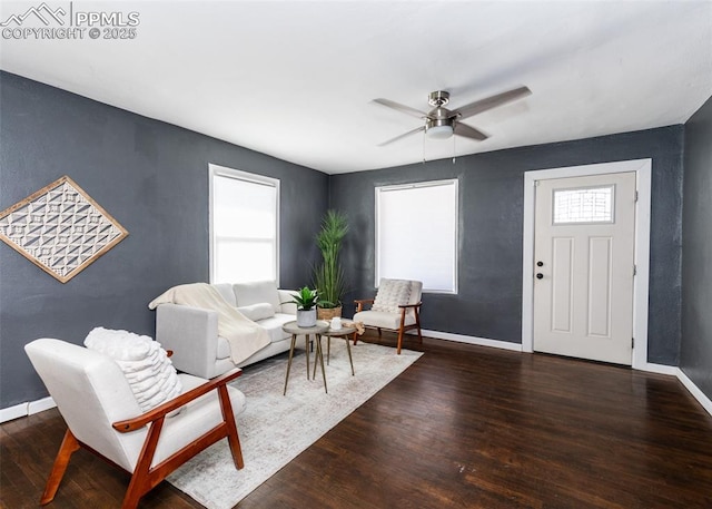 living area featuring dark wood-style floors, baseboards, and a ceiling fan