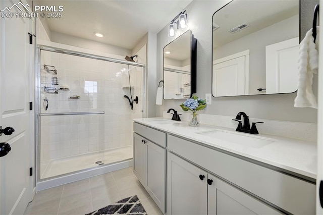 bathroom with a shower with door, vanity, and tile patterned floors