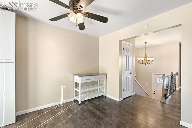 unfurnished room featuring dark hardwood / wood-style flooring and ceiling fan with notable chandelier