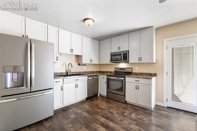 kitchen with stainless steel appliances, white cabinetry, sink, and dark hardwood / wood-style flooring