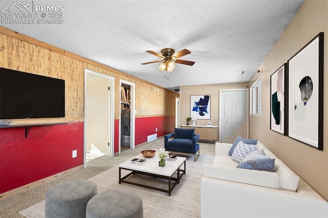 carpeted living room with ceiling fan and a textured ceiling