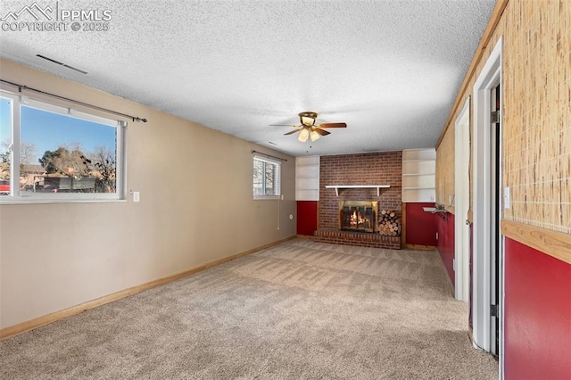 unfurnished living room with ceiling fan, a brick fireplace, light carpet, and a textured ceiling