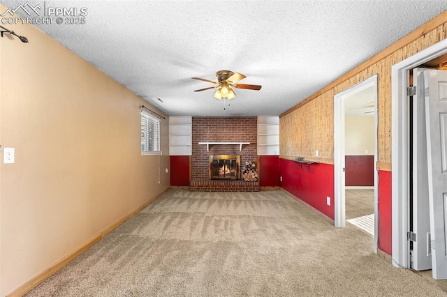 unfurnished living room with ceiling fan, carpet floors, a fireplace, and a textured ceiling