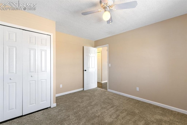 unfurnished bedroom featuring ceiling fan, a textured ceiling, dark carpet, and a closet