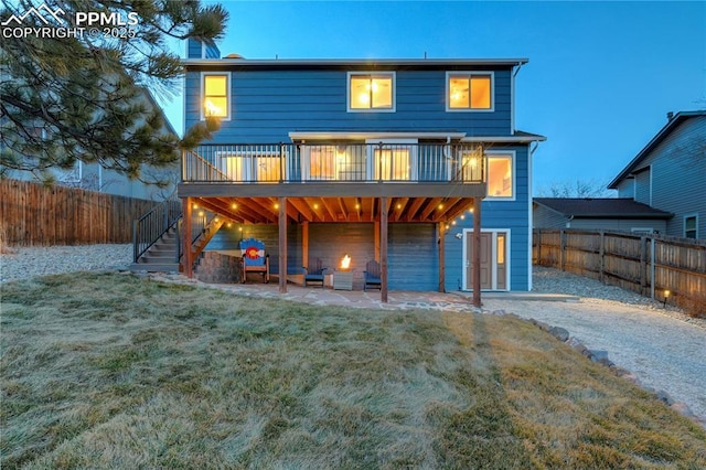 back house at dusk featuring a yard, an outdoor hangout area, a deck, and a patio