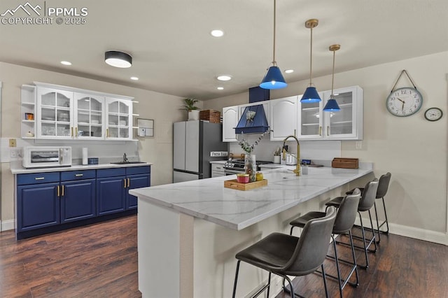 kitchen with stainless steel refrigerator, blue cabinets, light stone counters, and white cabinets