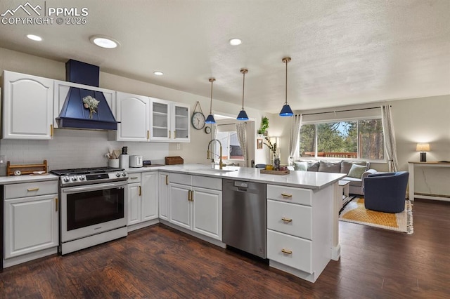 kitchen featuring pendant lighting, sink, stainless steel appliances, white cabinets, and kitchen peninsula