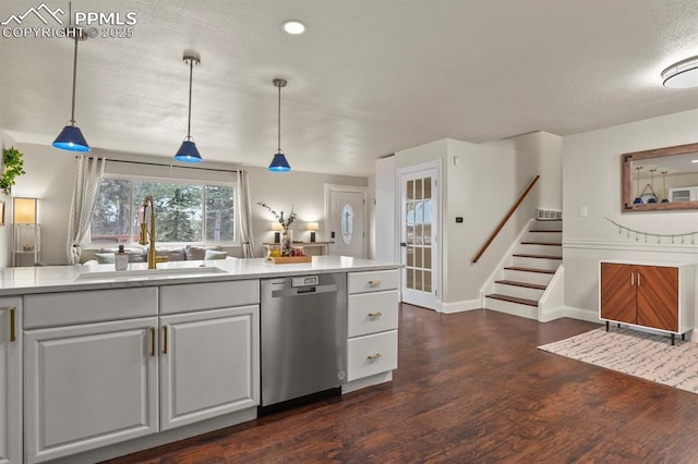 kitchen with pendant lighting, sink, dark wood-type flooring, white cabinets, and stainless steel dishwasher