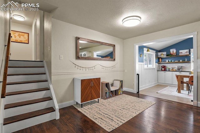 entryway featuring vaulted ceiling, dark wood-type flooring, and a textured ceiling