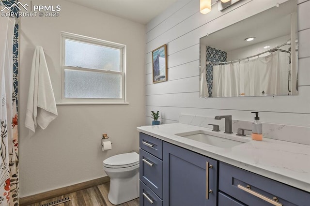 bathroom with toilet, wood-type flooring, vanity, wooden walls, and curtained shower