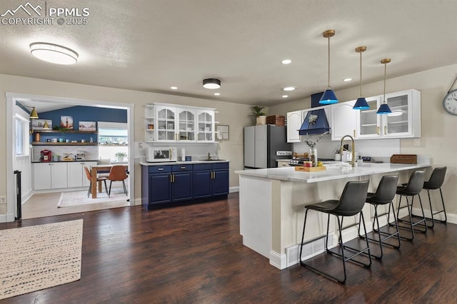 kitchen with blue cabinets, white cabinetry, dark hardwood / wood-style floors, and stainless steel refrigerator