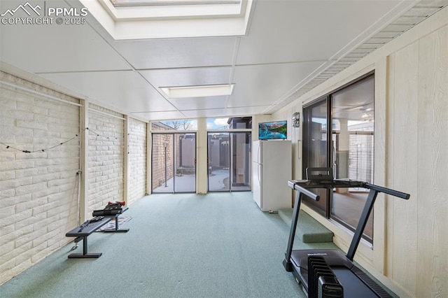 exercise room featuring light colored carpet and brick wall