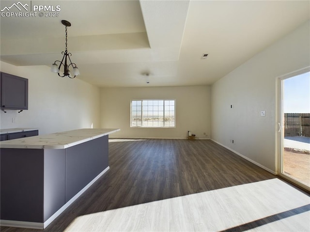 kitchen featuring dark wood-type flooring, gray cabinetry, light stone counters, hanging light fixtures, and a notable chandelier