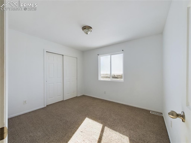 unfurnished bedroom featuring dark carpet and a closet