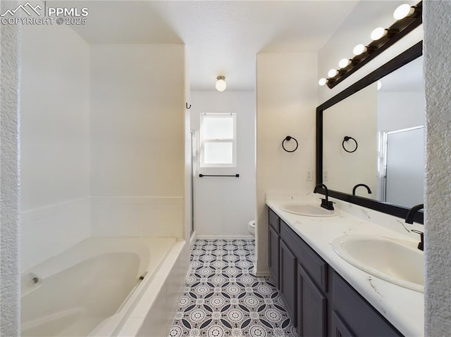 bathroom featuring tile patterned flooring, tiled tub, vanity, and toilet