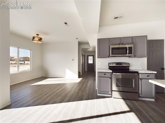 kitchen with appliances with stainless steel finishes, dark hardwood / wood-style floors, and gray cabinets