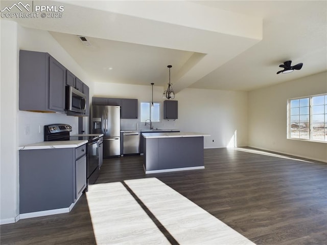 kitchen featuring sink, gray cabinetry, appliances with stainless steel finishes, a kitchen island, and pendant lighting