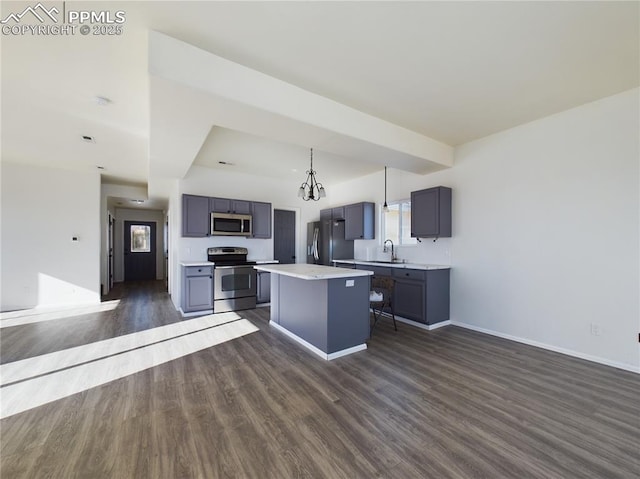 kitchen with a kitchen island, appliances with stainless steel finishes, pendant lighting, gray cabinetry, and dark hardwood / wood-style flooring