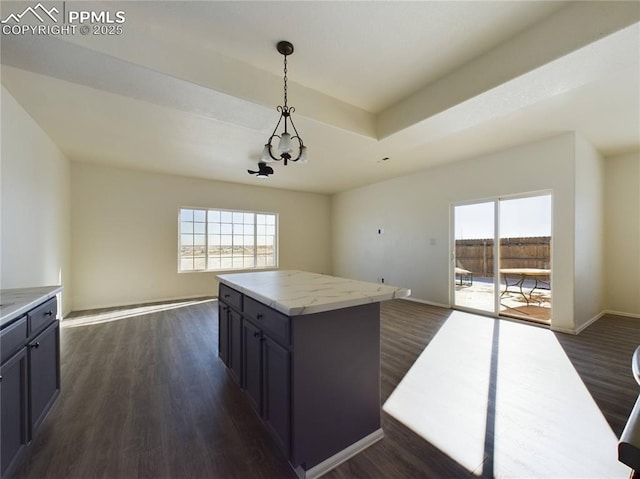 kitchen featuring hanging light fixtures, a center island, light stone counters, a tray ceiling, and dark wood-type flooring