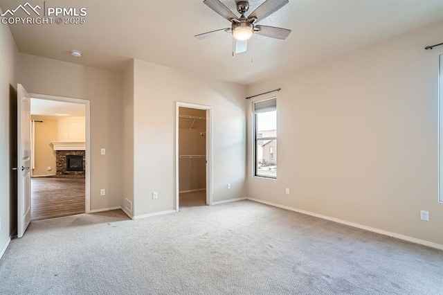 unfurnished bedroom with carpet, baseboards, a fireplace, a spacious closet, and a closet