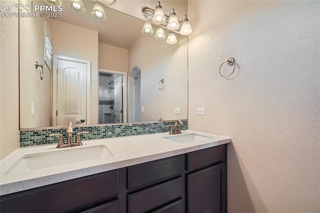 bathroom featuring double vanity, backsplash, and a sink