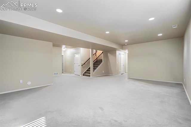 finished below grade area with visible vents, baseboards, recessed lighting, stairs, and light colored carpet