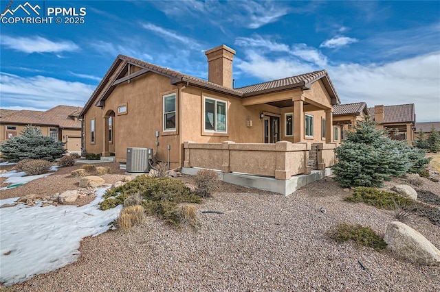 exterior space with fence, a tile roof, stucco siding, cooling unit, and a chimney