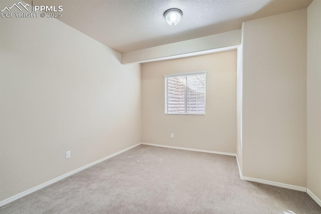 spare room with baseboards, carpet floors, and a textured ceiling