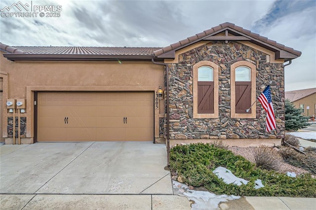 view of front of house with stucco siding, concrete driveway, a garage, stone siding, and a tiled roof