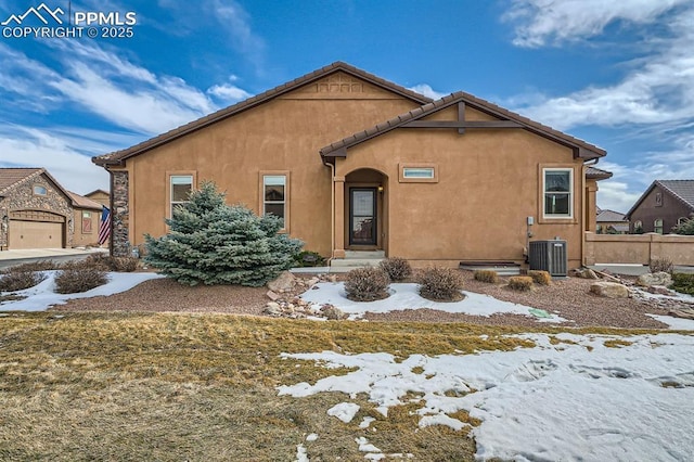 view of front of house with stucco siding, a tile roof, central AC, and fence