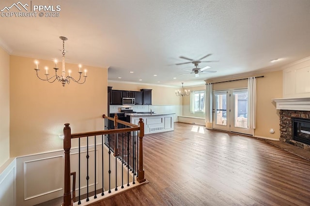 living room featuring dark wood finished floors, a wainscoted wall, ornamental molding, and a fireplace