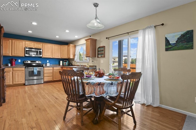 kitchen featuring sink, hanging light fixtures, light hardwood / wood-style flooring, appliances with stainless steel finishes, and stone counters