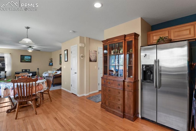 kitchen featuring hanging light fixtures, light hardwood / wood-style flooring, ceiling fan, and stainless steel fridge with ice dispenser