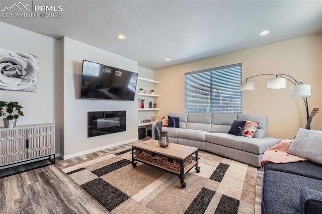 living room with built in features, hardwood / wood-style floors, and a textured ceiling