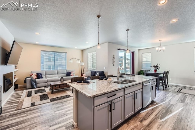 kitchen with sink, gray cabinets, a kitchen island with sink, decorative light fixtures, and stainless steel dishwasher